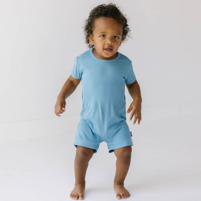 A baby wearing a solid blue short-sleeved romper.