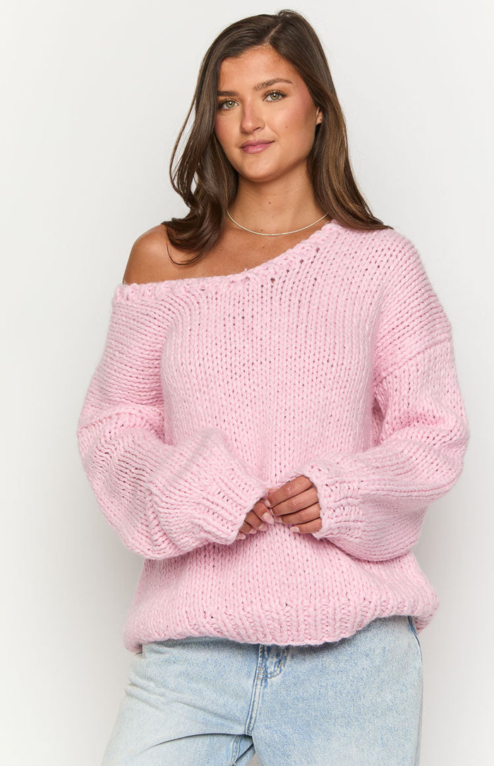 Light pink chunky knit sweater with an off-the-shoulder neckline and wide ribbed cuffs